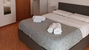 Una habitación de hotel con cama, armario, espejo y mesita de noche.