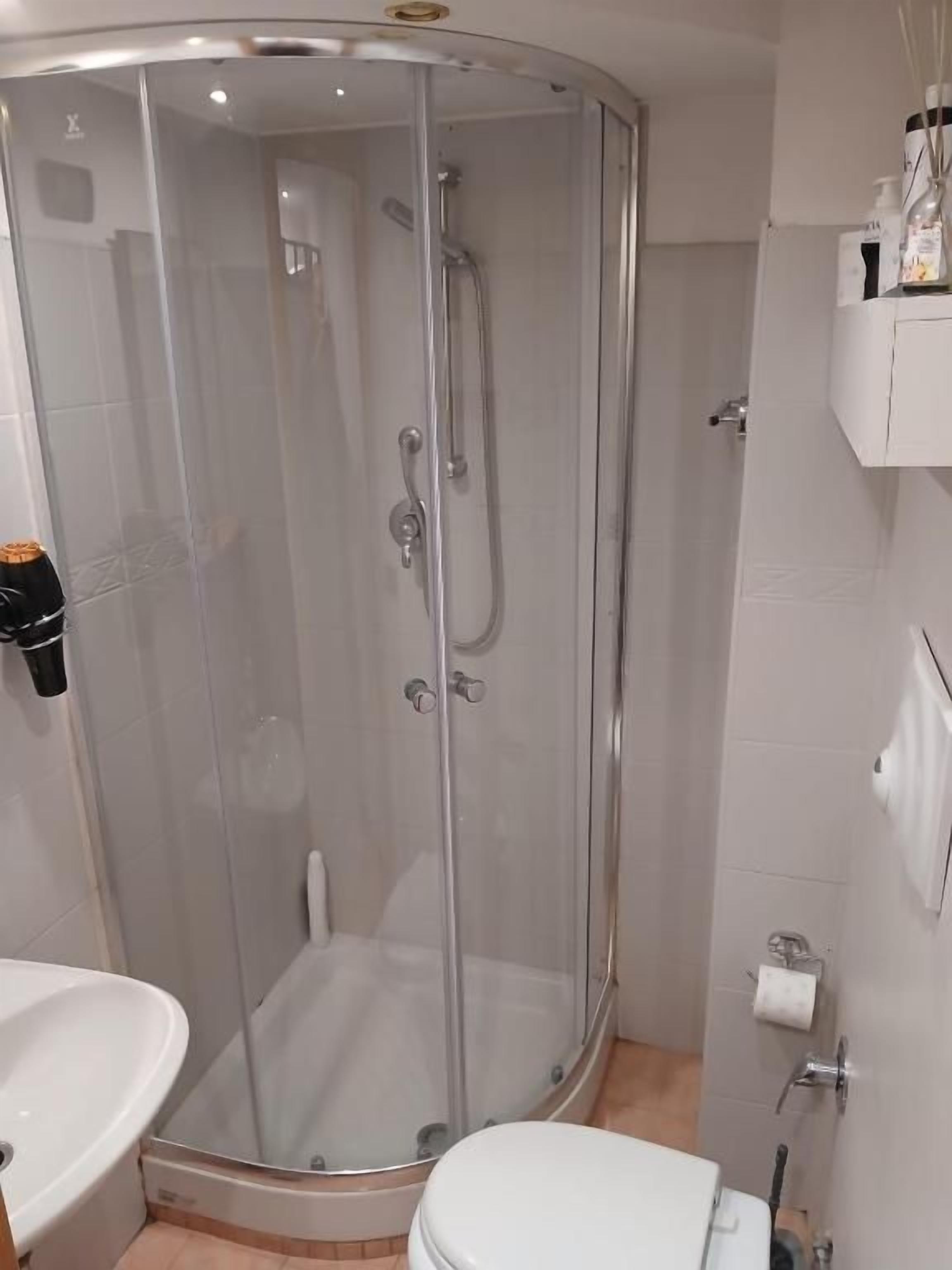 Un baño con ducha de vidrio, inodoro y lavamanos.