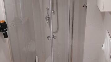 Un baño con ducha de vidrio, inodoro y lavamanos.