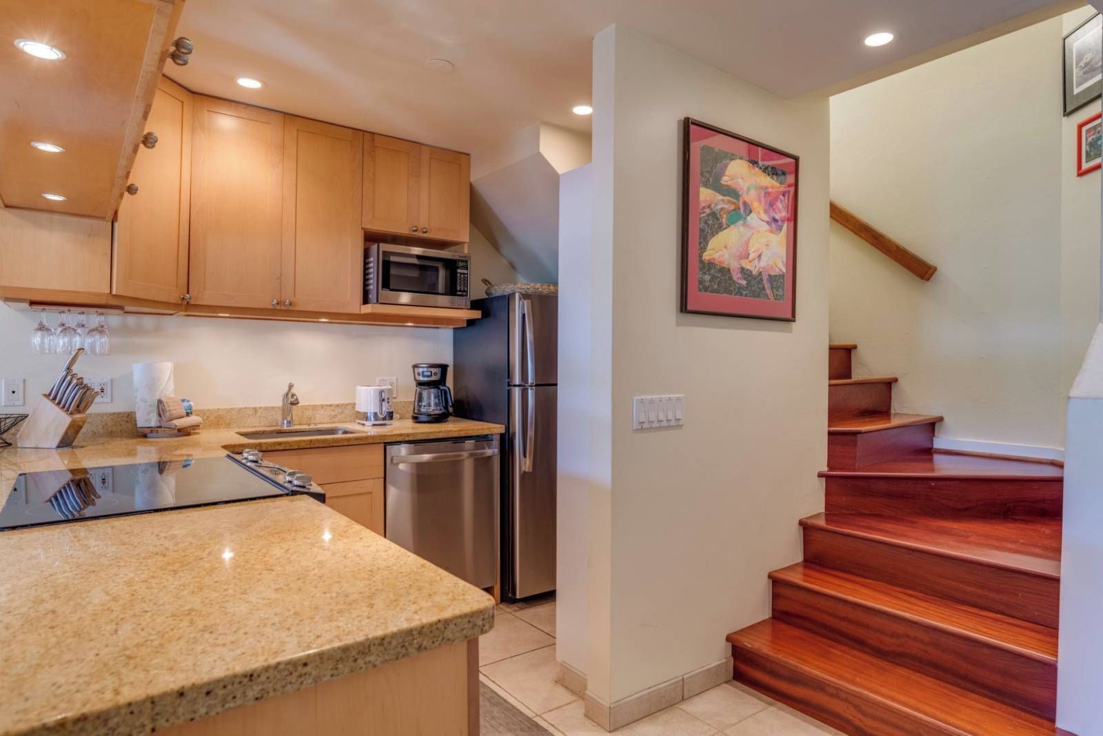 A kitchen with wooden cabinets, a stainless steel refrigerator, a microwave, and a coffee maker.