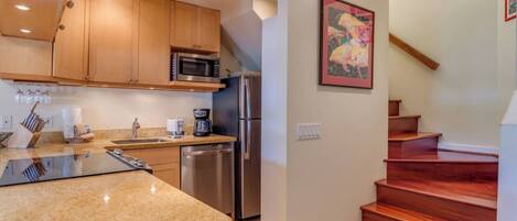 A kitchen with wooden cabinets, a stainless steel refrigerator, a microwave, and a coffee maker.