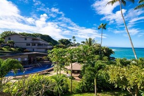 Um imóvel residencial com piscina, vegetação exuberante e vista para o oceano.