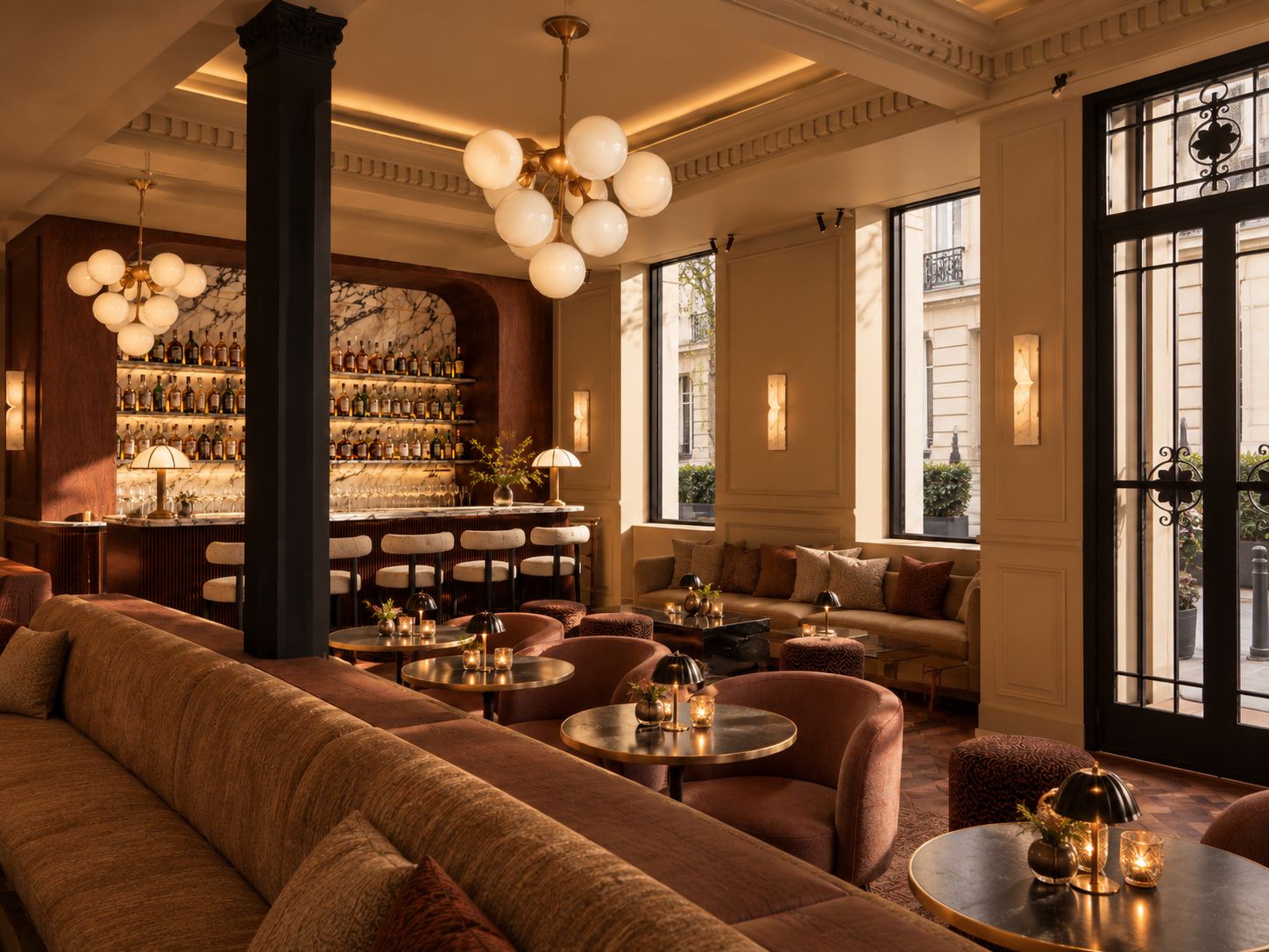 Een bar met een marmeren wand, diverse zitplaatsen zoals banken en ronde tafels, en een kroonluchter.