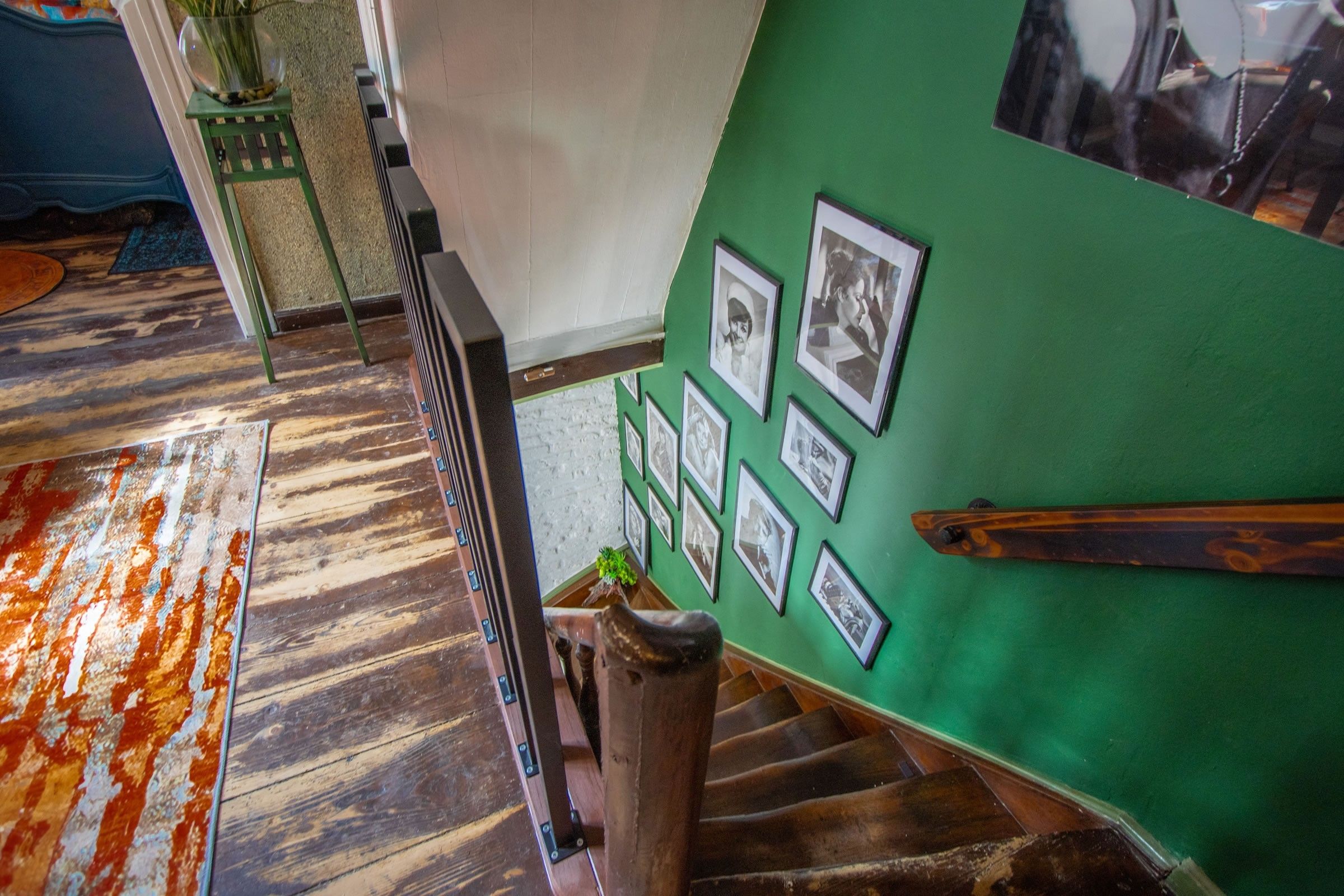 Eine Treppe mit einer grünen Wand, die mit gerahmten Fotos verziert ist.