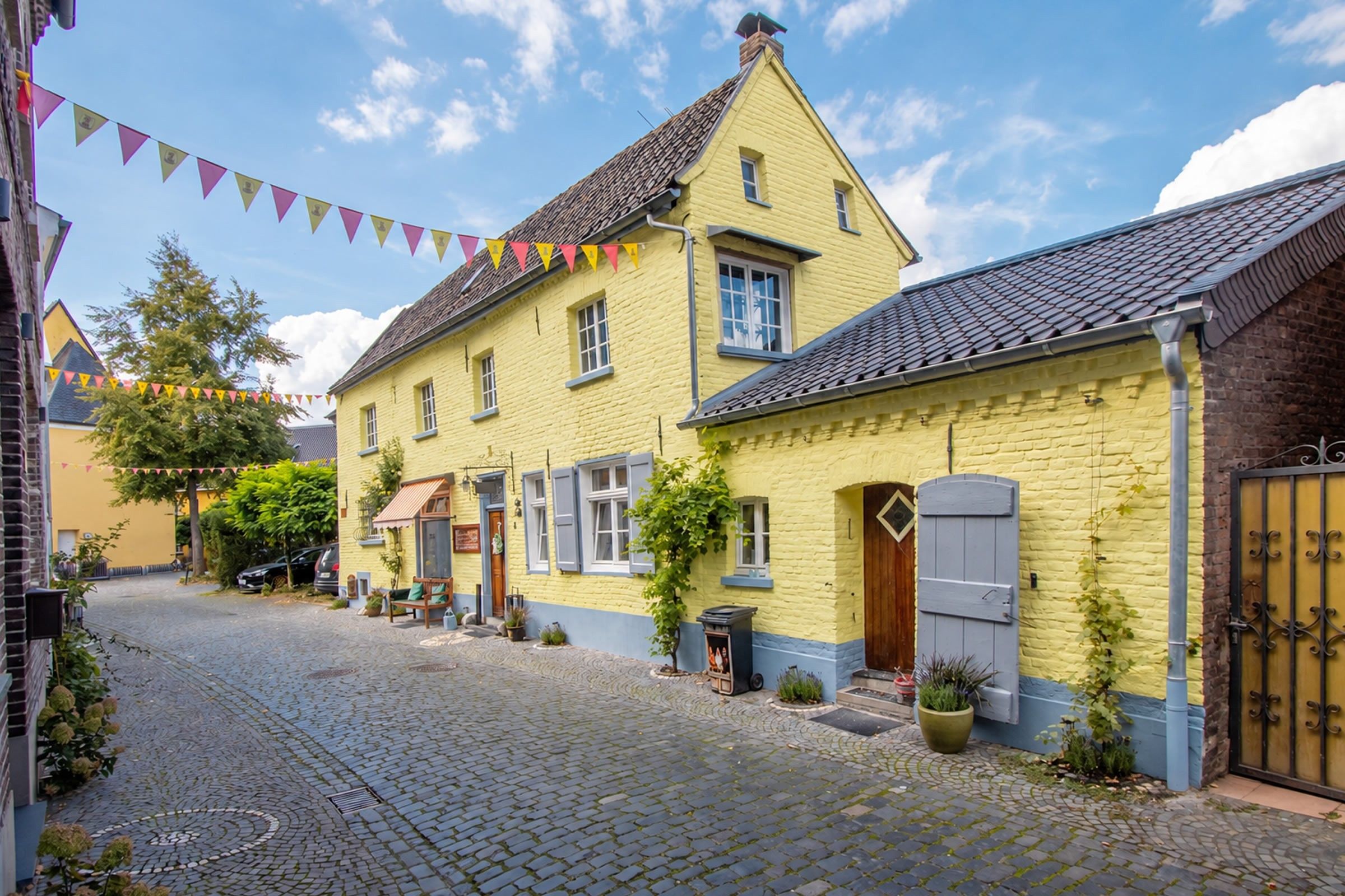 A cobblestone street lined with yellow buildings, some with shutters, and a clear sky.