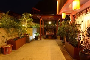 Un camino exterior bien iluminado que conduce a un edificio de estilo tradicional con faroles y plantas en macetas.