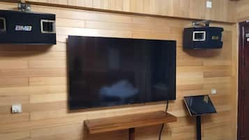 A flat-screen TV mounted on a wooden wall with a bench below.