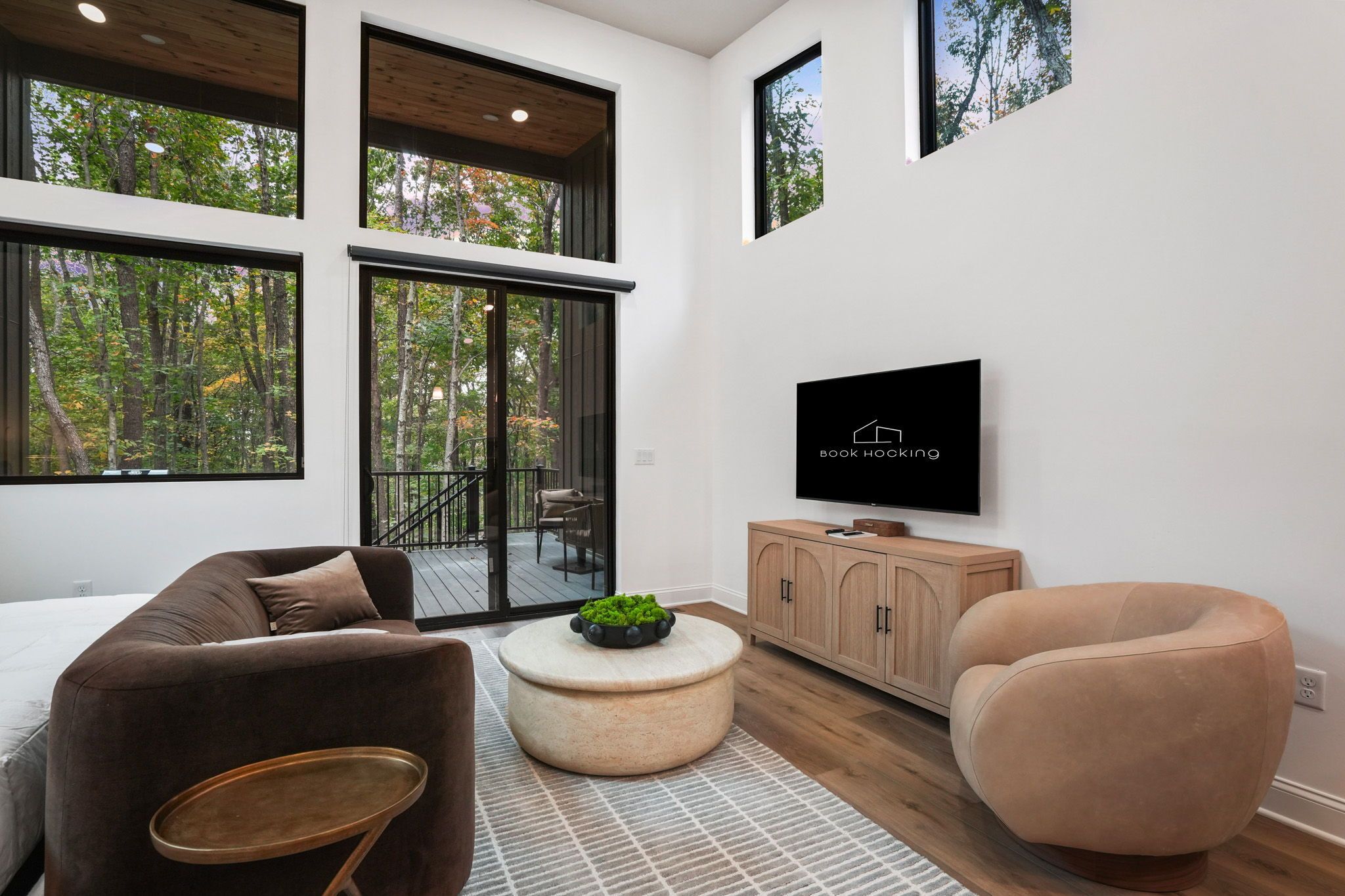 A modern living room with a sofa, armchair, coffee table, and a TV mounted on the wall.