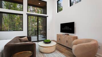 A modern living room with a sofa, armchair, coffee table, and a TV mounted on the wall.