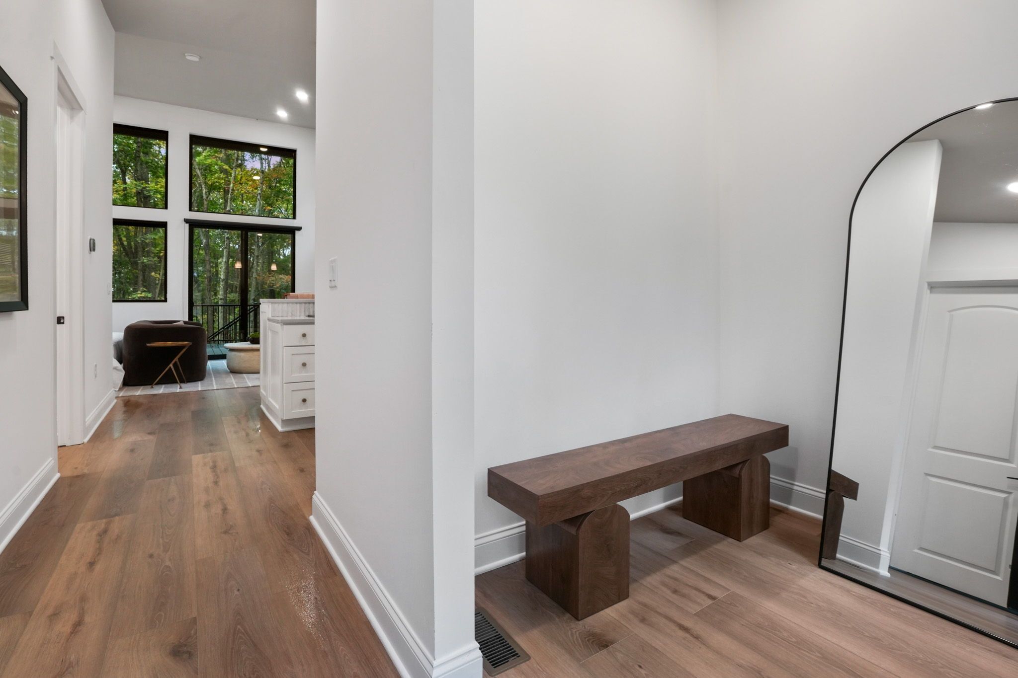 A hallway with a wooden floor, a bench, and a door.