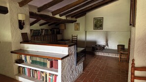 Ein Zimmer mit Bücherregal, Tisch, Stuhl und Kamin.