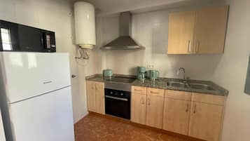 Una cocina compacta con refrigerador, estufa, pileta y alacenas.