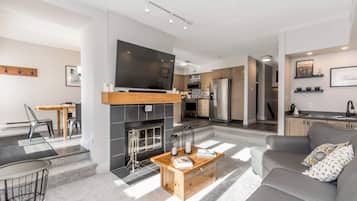 A modern living room with a fireplace, a flat-screen TV, and a sofa.