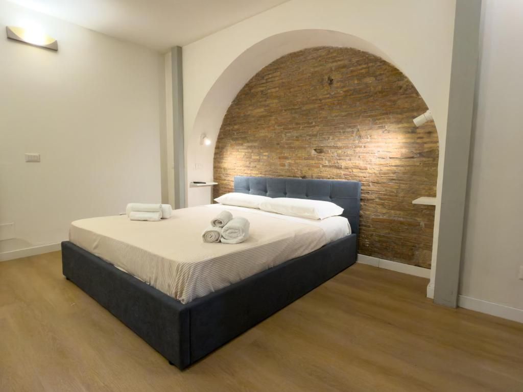 A bedroom with a bed, a brick wall, and a wooden floor.