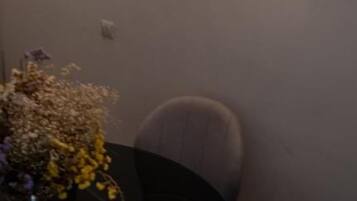 Un área de comedor con una mesa y sillas, un florero con flores y cuadros en la pared.
