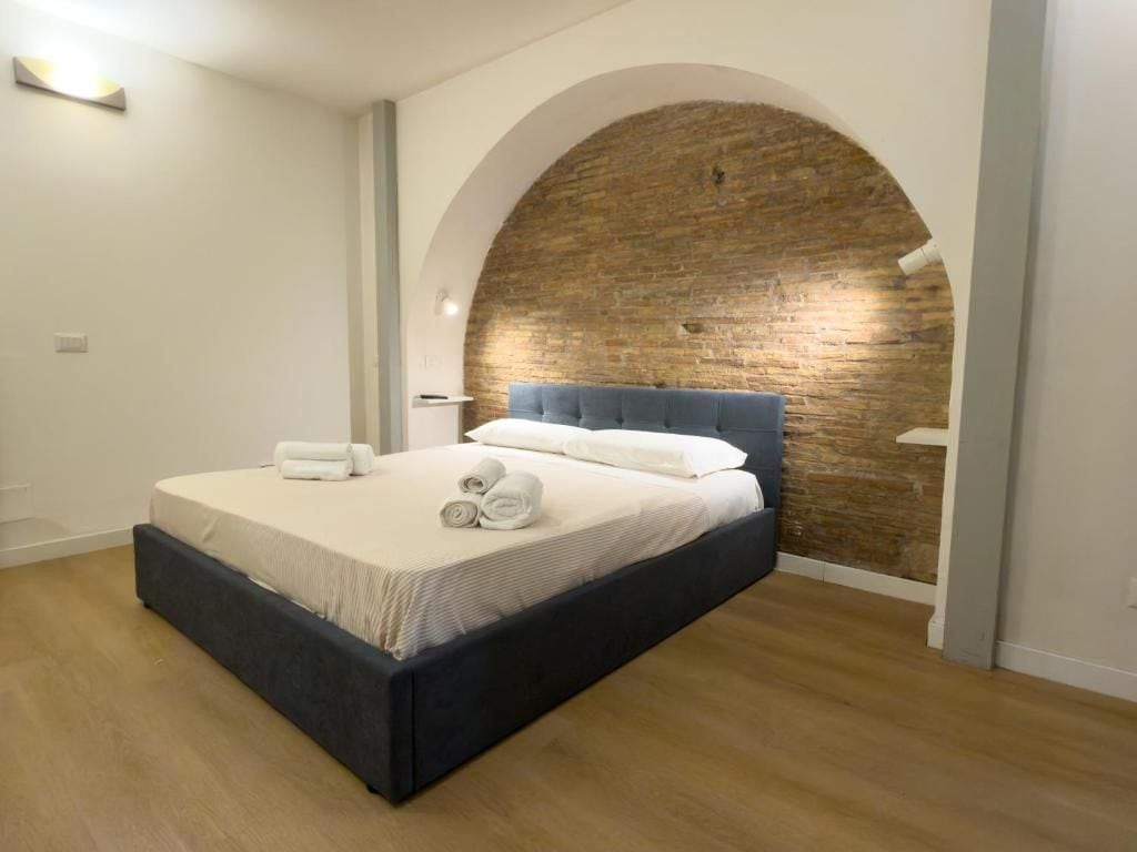 A bedroom with a bed, a brick wall, and a wooden floor.