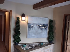 A wall-mounted painting of a landscape, a wall-mounted lantern, and two potted plants. - Beautiful 6 Bedroom 3.5 Bath Home with Heated Pool and Jacuzzi and Steam Rooms (Hales Corners)