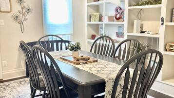 A dining area with a table, chairs, and a patterned rug.