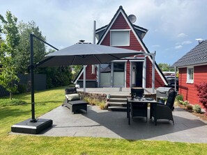 En terrasse med udendørs møbler, grill og en parabolantenne på et hus.