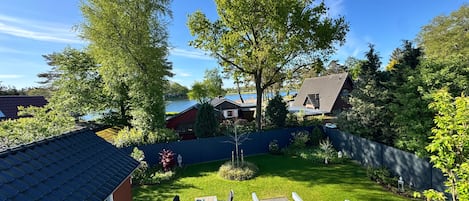 A residential property with a fenced backyard, a patio with outdoor furniture, and a view of a lake.