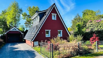 A red house with a sloped roof, a garage, and a paved driveway.
