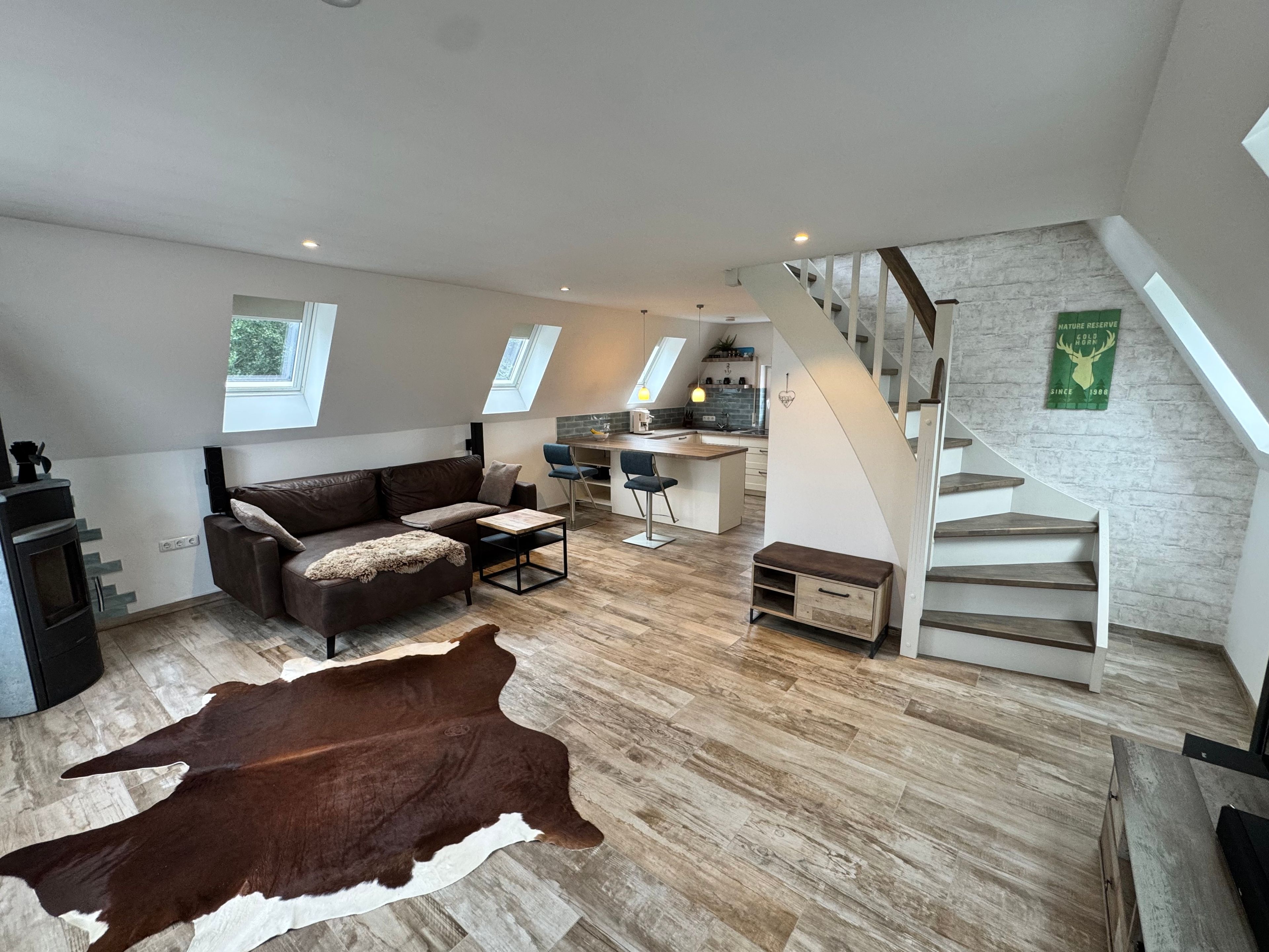 Un intérieur moderne avec un espace de vie aménagé dans le style d’un loft, une cuisine et un escalier.