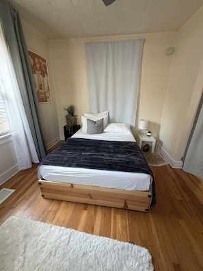 A bedroom with a bed, a nightstand, a lamp, a window with curtains, a wall art piece, and a fluffy rug. - 3- bedrooms residential home (Albuquerque)