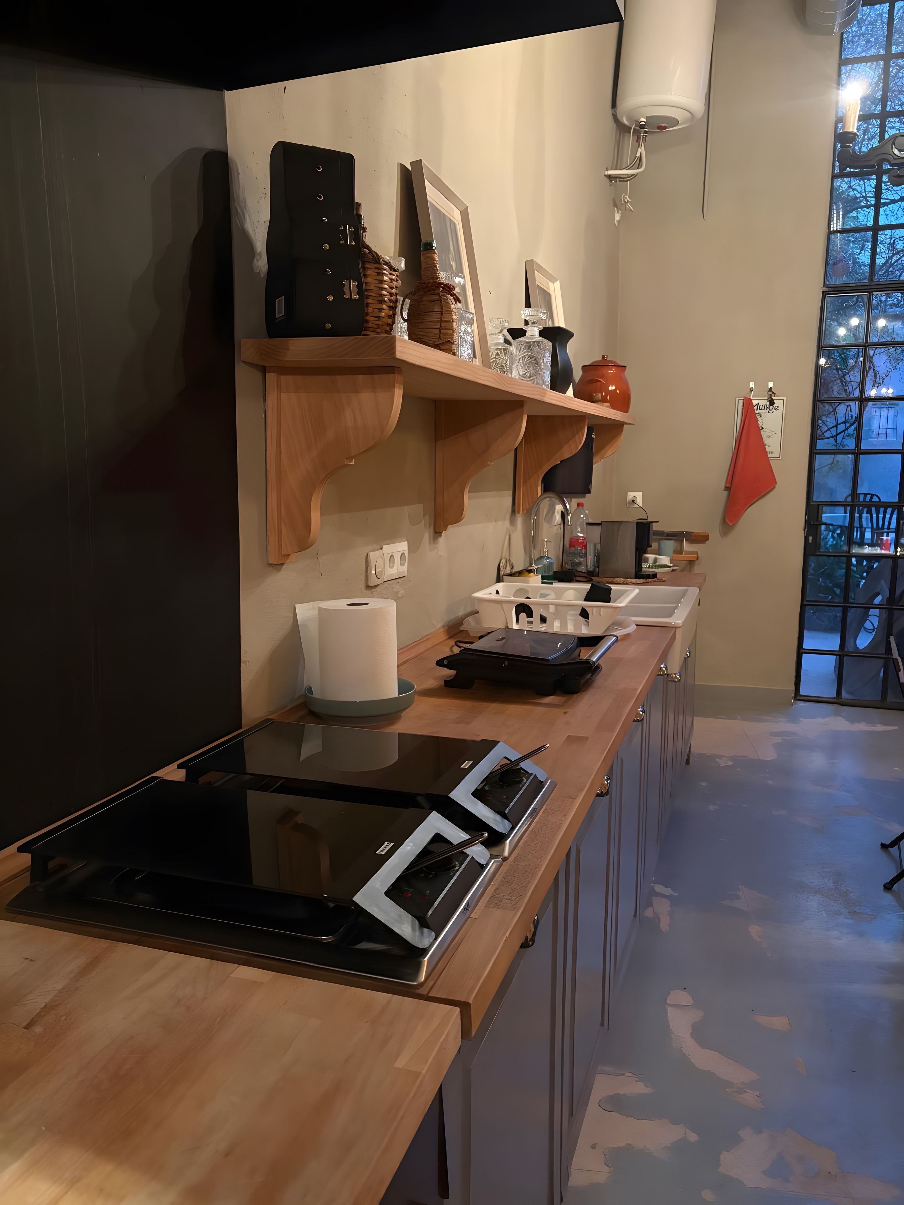 A modern kitchen with a built-in stove, wooden shelves, and a window with a view.