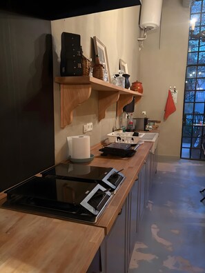 Una cocina moderna con estufa integrada, repisas de madera y ventana con vistas.