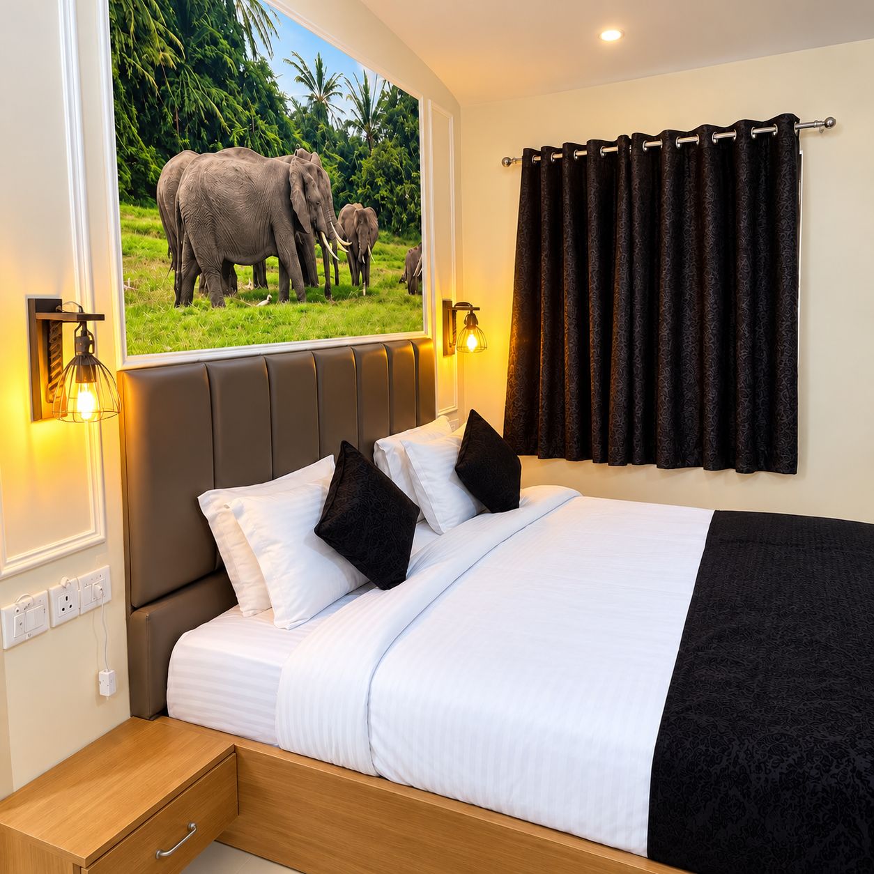 Une chambre d’hôtel avec un lit, une table de chevet, une lampe fixée au mur, une fenêtre donnant sur un paysage où l’on peut apercevoir des éléphants, et un rideau.