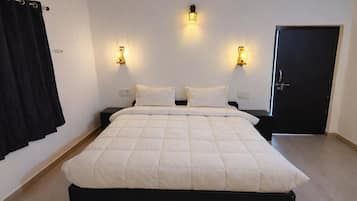 A bedroom with a bed, two bedside lamps, a door, and a curtain.