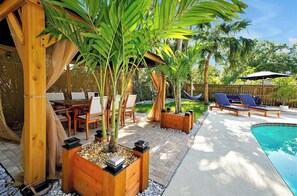 A poolside area with a wooden pergola, lounge chairs, and potted plants. - New Listing (Kissimmee)