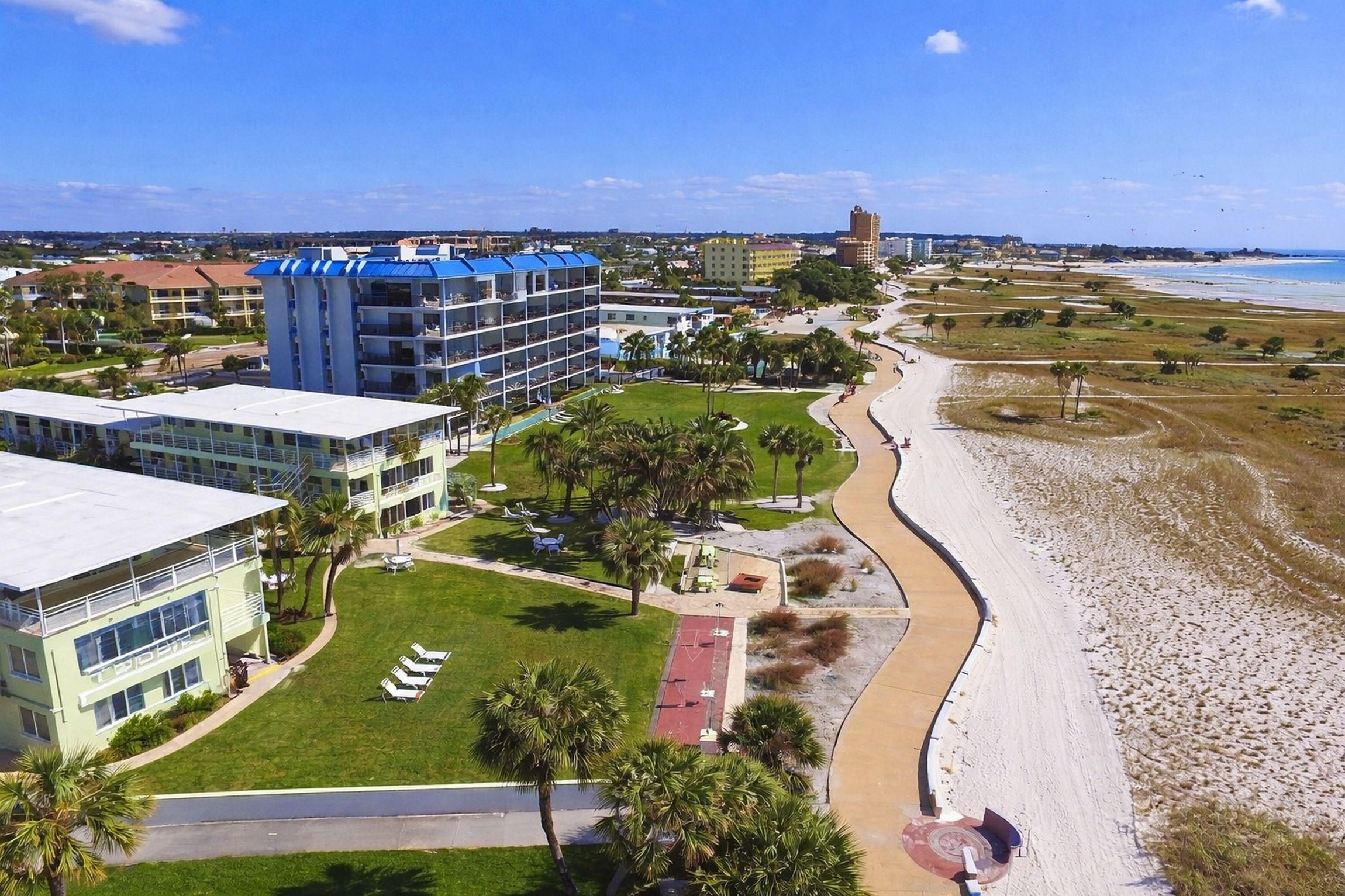 A coastal hotel with multiple buildings, a beach, and a clear sky.
