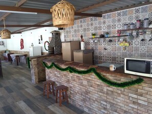 Cozinha com bancada de tijolos, micro-ondas e luminária pendente.