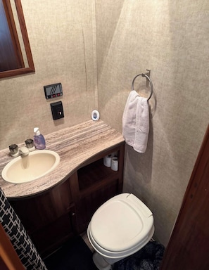 Een badkamer met een marmeren wastafel, een toilet en een handdoekrek.