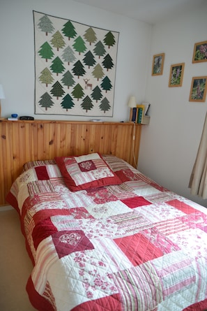 A bedroom with a wooden headboard, a quilted bedspread, and a wall hanging of trees. - New Listing (luz saint sauveur)