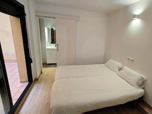 Ein Schlafzimmer mit einem Bett, einer Tür zu einem Badezimmer und Blick ins Freie.