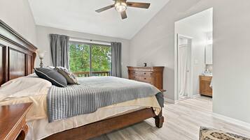 A bedroom with a wooden bed, a ceiling fan, a window with curtains, and a wooden dresser.