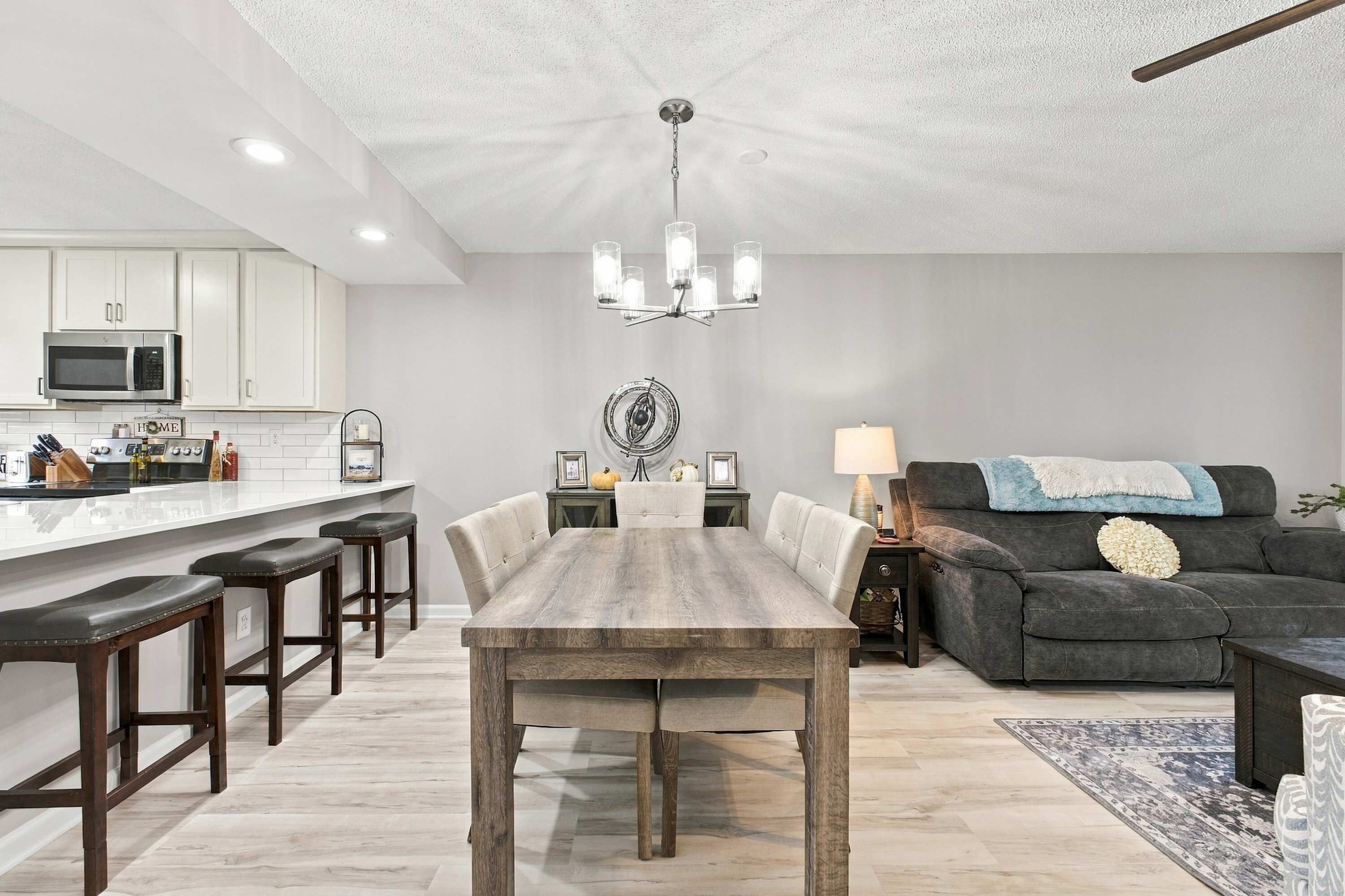 A modern kitchen with white cabinets, a central island, and a dining area with a wooden table and chairs.