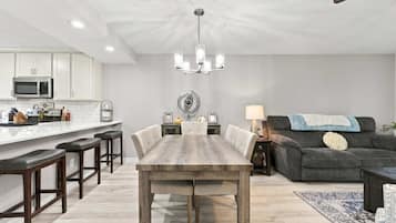 A modern kitchen with white cabinets, a central island, and a dining area with a wooden table and chairs.