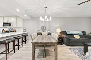 Eine moderne Küche mit weißen Schränken, einer zentralen Kochinsel und einem Essbereich mit Holztisch und Stühlen.