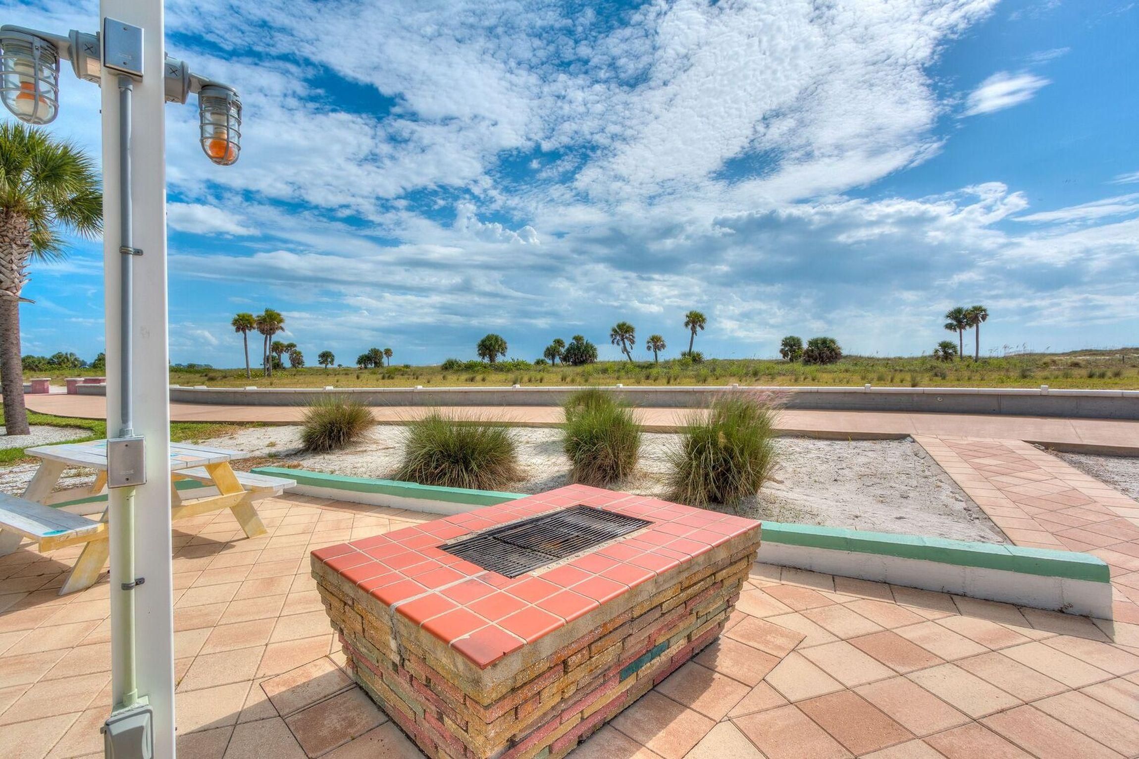 A paved outdoor area with a brick planter, a street lamp, and a clear sky with clouds.