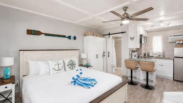 Une chambre d’hôtel moderne dotée d’un grand lit, d’un ventilateur de plafond, d’un coin cuisine et d’une salle de bain.