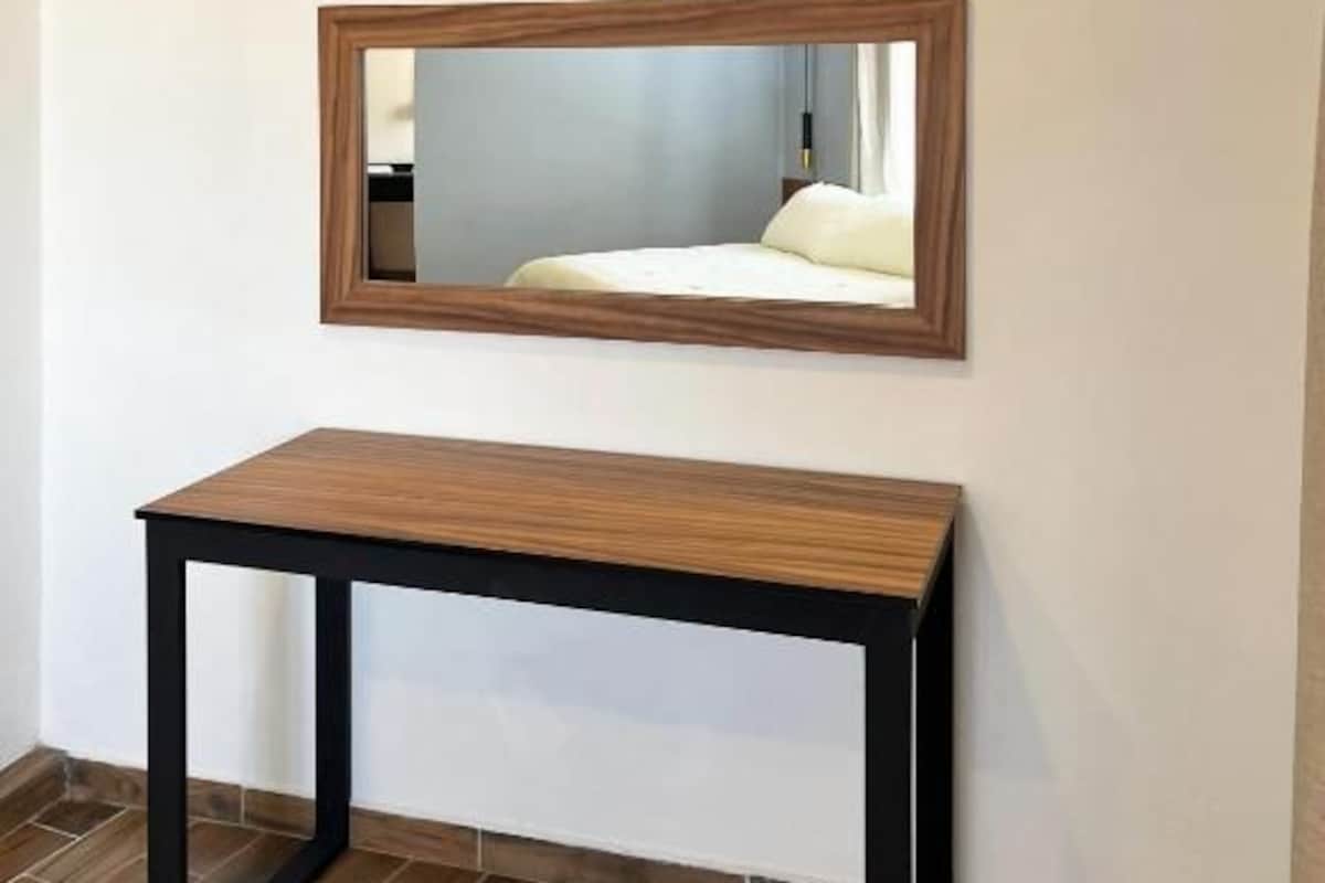 Quarto com uma mesa de madeira e um espelho na parede.