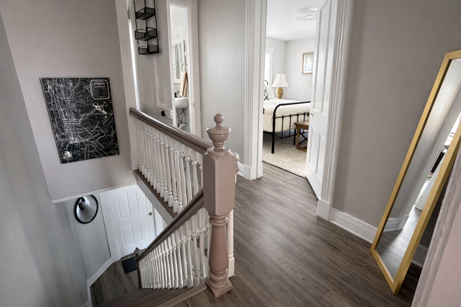 A staircase with a wooden handrail leading to a room with a bed and a table.