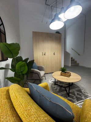 Una sala de estar moderna con un sofá, una mesa redonda de centro y una planta grande.