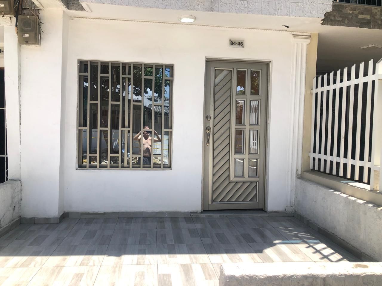 A building with a gated entrance, a window with bars, and a tiled ground.