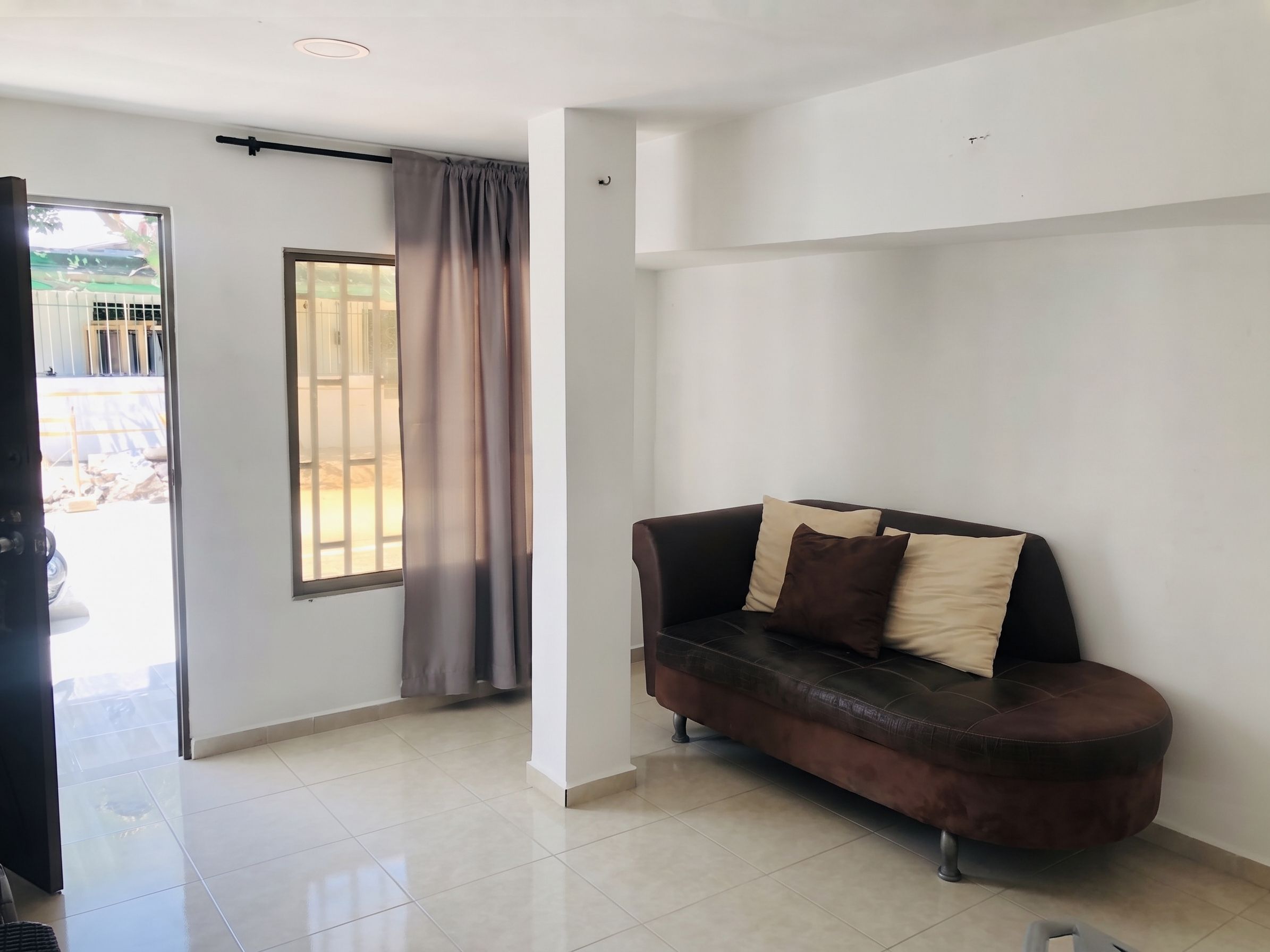 A living room with a sofa, a sliding glass door, and a tiled floor.
