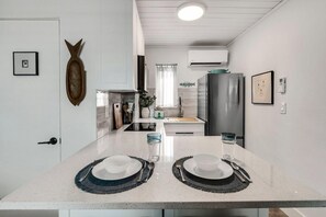 Una cocina moderna con una isla central, armarios blancos y un refrigerador de acero inoxidable.