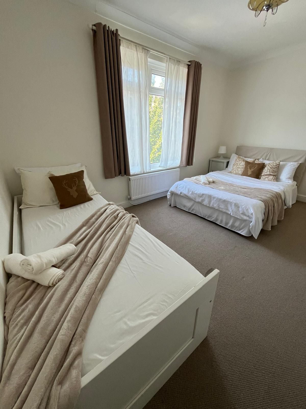 Habitación de hotel con dos camas, un radiador y una ventana con cortinas.